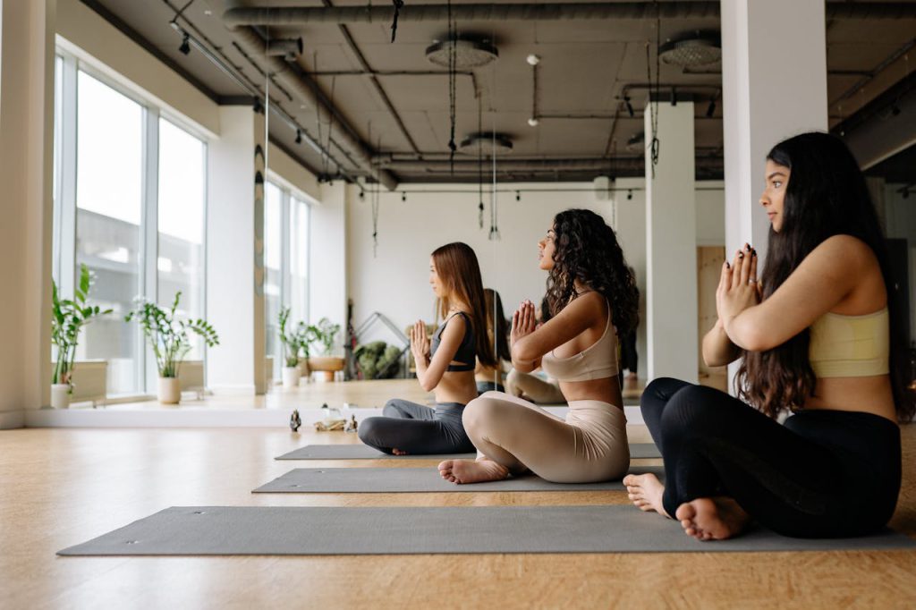 Group of women focused on meditation and yoga pose in a modern indoor studio.