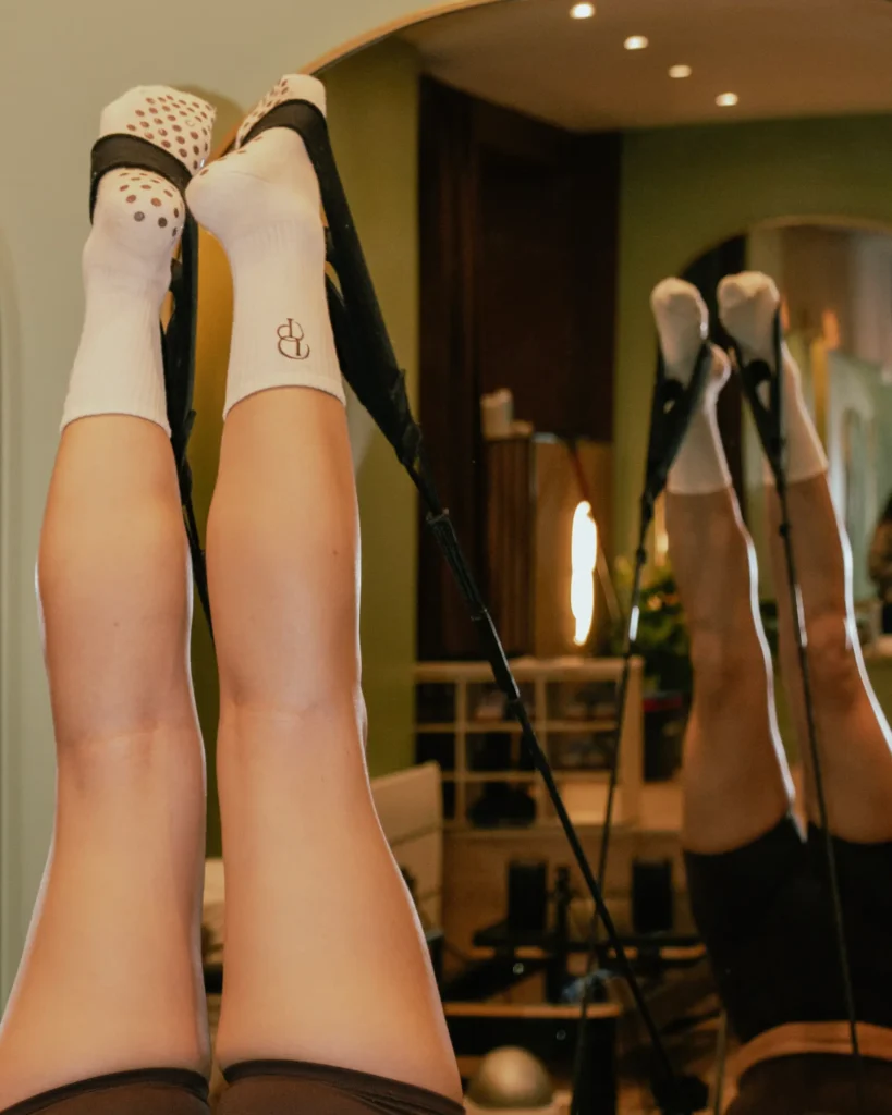 Élève en position de Pilates avec les pieds vers le haut maintenus par des élastiques